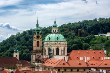 Towers with green domes of the Church of St. Nicholas in the Czech city of Prague.