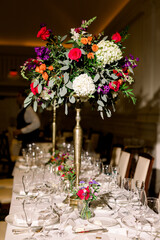 Beautiful colorful wedding centerpiece at a head table at a wedding. Luxury wedding with glasses and white table cloth.