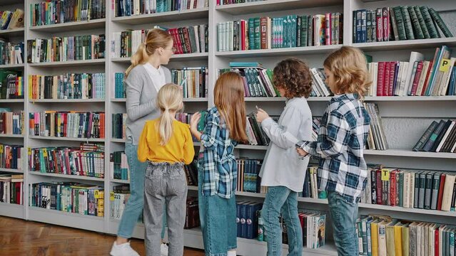 Blonde teacher helps children to find necessary books