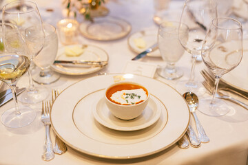 Tomato soup served on a fancy dinner restaurant with plates and silverware and glassware
