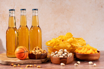 Beer in bottle and snack on wooden table with basketball ball, game night food