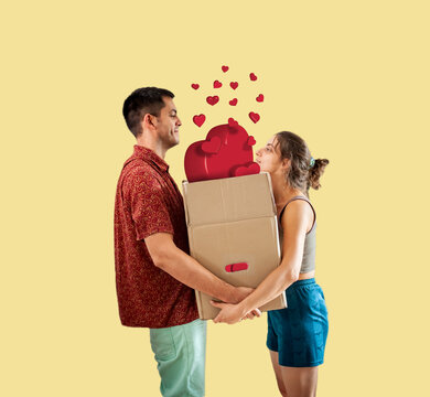 Young cheerful romantic couple standing and holding a box with red hearts. Digitally generated red hearts are their emotions, love and memories.