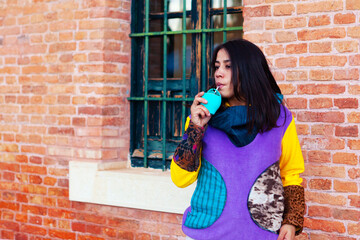 Latin american brunette girl drinking mate with colorful hoodie
