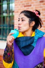 Portrait of latin american brunette girl drinking mate with colorful hoodie
