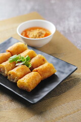 Fried Egg Rolls, Vegetable Rolls, Fried chinese spring rolls with sweet chili sauce served in a black plate in a restaurant.