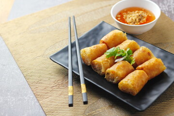 Fried Egg Rolls, Vegetable Rolls, Fried chinese spring rolls with sweet chili sauce served in a black plate in a restaurant.