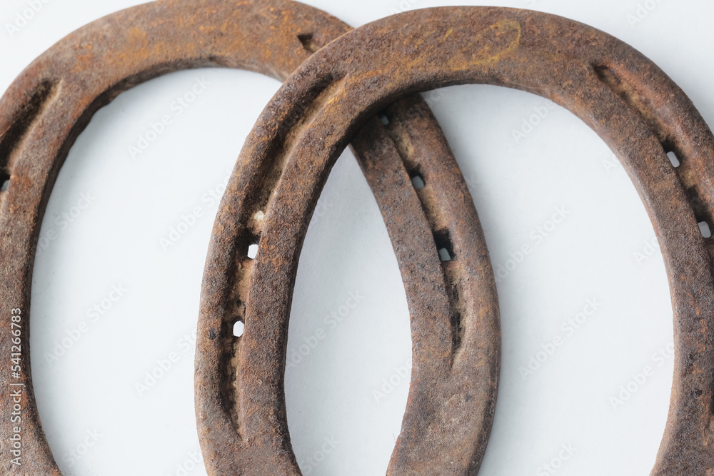 Poster Old iron horseshoes on white background closeup for equine industry concept. - Posters