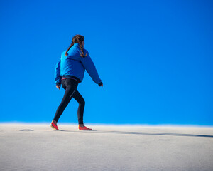 a girl walks along the top of a huge sand dune in coral bay western australia; walking in the sandy...