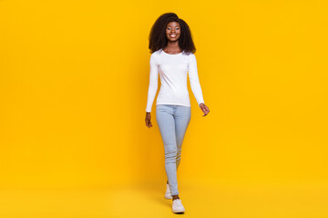 Full size portrait of cheerful pretty lady walking have good mood isolated on bright yellow color background - Powered by Adobe