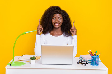 Portrait of cheerful charming person indicate fingers up empty space use wireless netbook isolated on yellow color background