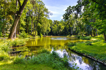 Historic park surrounding XVI century Rozalin Palace with vintage trees and ponds during summer season in Rozalin village in Mazovia region of Poland