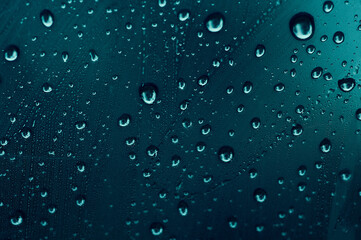 The texture of the drops on the glass. Blue background. Sweaty surface. Car window.