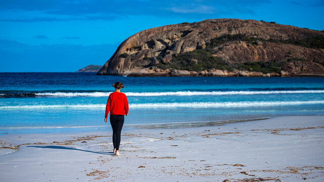 happy girl runs and jumps on lucky bay beach in western australia; sunny day on paradise beach with turquoise water, white sand and mountain in the background