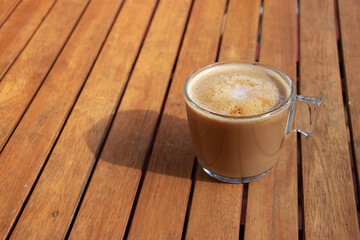 Fresh coffee on a wooden table during breakfast. The sun falls on the cup. Time to relax