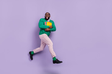 Fototapeta na wymiar Full body image of excited young teacher running to his classroom hold class materials isolated on violet color background