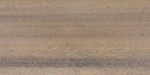 top view of surface of gravel road made of small stones and sand with traces of car tires