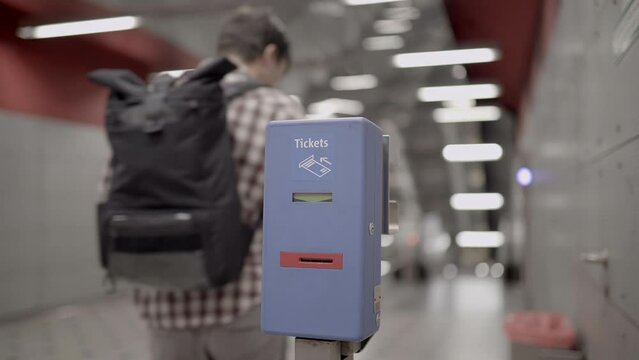 Passenger inserts ticket into validator to mark the time. Munich metro, subway, streetcar, bus all public transport. Man marks his ticket into public transport validation machine at metro station. 