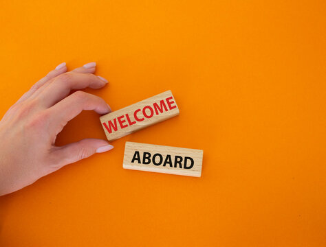 Welcome aboard symbol. Concept word Welcome aboard on wooden blocks. Beautiful orange background. Businessman hand. Business and Welcome aboard concept. Copy space