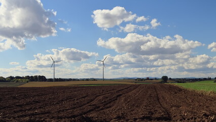 Electricity generating windmills overlooking fields and mountains