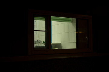 Window in building. Single window. Light in dark interior. Glass in evening.