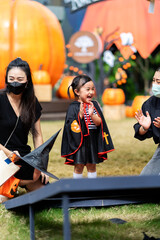 Happy asian little girl in a witch costume having fun during playing games in Halloween party.