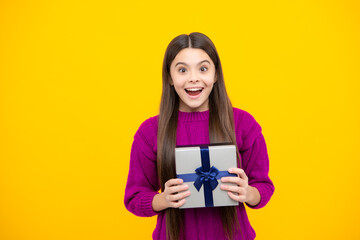 Teenager child holding gift box on yellow isolated background. Gift for kids birthday. Christmas or New Year present box.