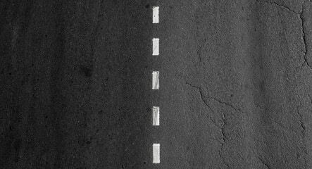Dotted dividing road marking line goes over asphalt highway