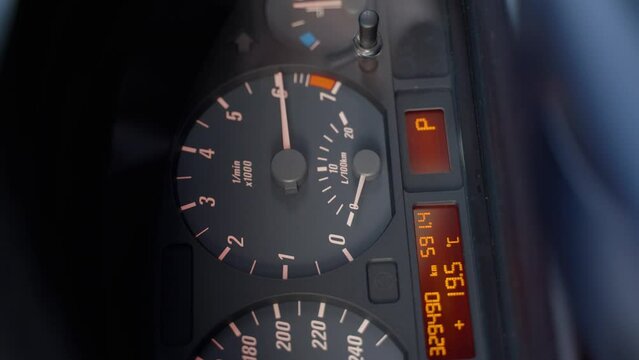 Black dashboard in a car. Tachometer circle. The tachometer needle moves and shows the engine speed. The red mark shows over-revving. Vertical video. Close-up