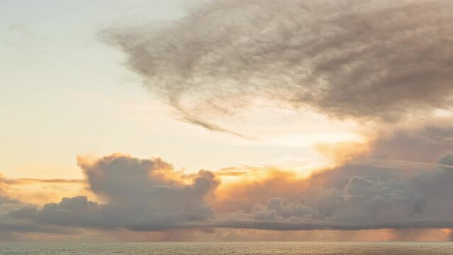 Cloudscape sunset over the ocean with rain and storm clouds above the horizon - timelapse