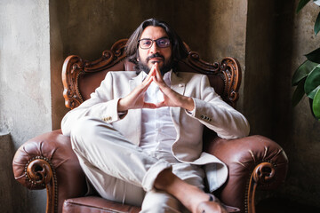Businessman sitting on the sofa in his office with imposing and powerful posture