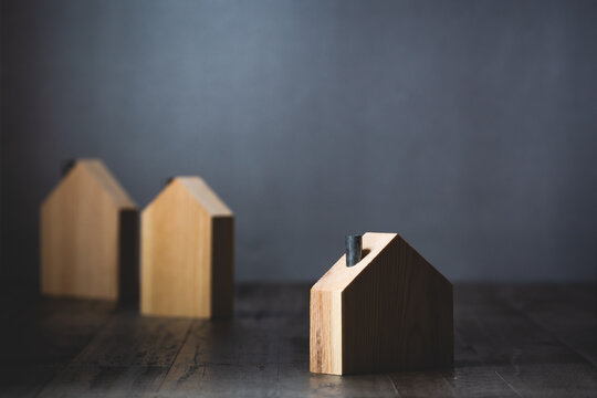 Lone wooden house isolated from other homes in shadow against gray background conceptual image