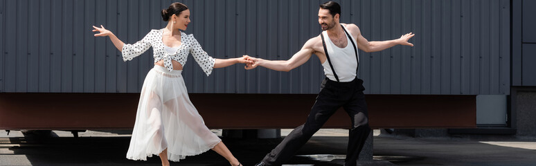 Pair of dancers performing choreography on roof of building, banner