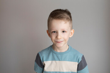 Portrait of a smiling boy 5-7 years old on a gray