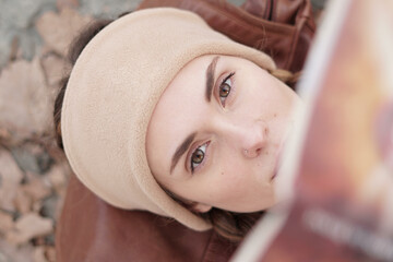 portrait view from above of a woman reading a book on an autumn day. Country woman with a turban, two braids and a plaid shirt. Autumn brown colors.