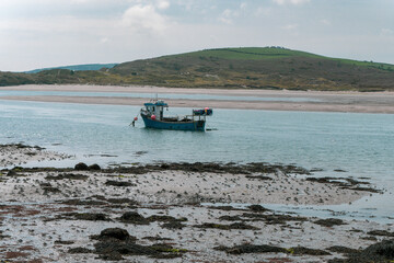Fototapeta na wymiar A small fishing boat moored near the shore at low tide. Seaside landscape. Sea.
