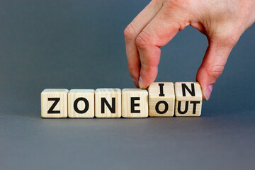 Zone in or out symbol. Concept words Zone in and Zone out on wooden cubes. Beautiful grey table grey background. Businessman hand. Business zone in or out concept. Copy space.