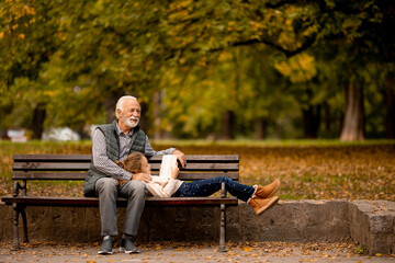 Fototapeta premium Grandfather spending time with his granddaughter on bench in park on autumn day