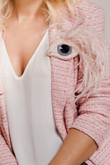 A woman in a tweed jacket with an eye-shaped brooch soft pink color