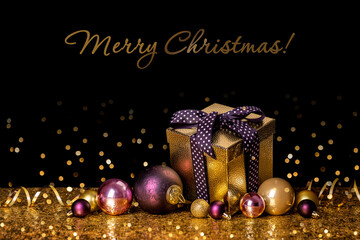 Merry christmas! Gift in a golden box with a bow on a black and gold background