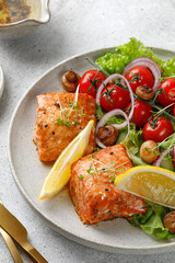 Baked  Salmon steak with fresh green salad with vegetables, tomatoes, onion. Keto diet concept healthy food, close up.