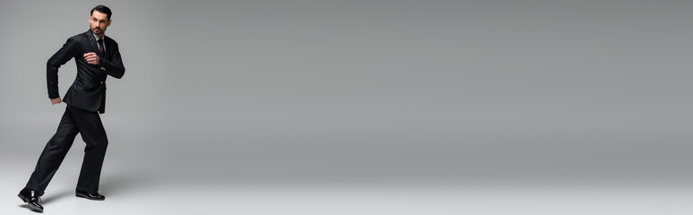 Professional ballroom dancer in suit dancing on grey background, banner