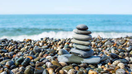 Pyramid of stones, against the backdrop of the blue sea. Pebble beach. Beach vacation.