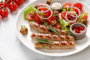 Fried grilled sausages with sauces, rosemary and salad on white plate. Close up. Dish, dinner idea.