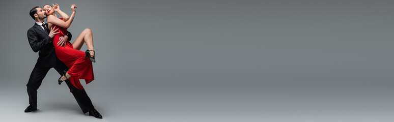 Professional dancers performing tango on grey background with copy space, banner