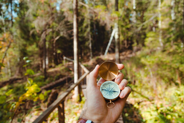 Hand with compass in forest terrain. POV Travel concept