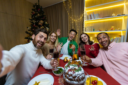 Video call for Christmas, various friends talking on a smartphone and taking a selfie joint photo sitting at home at the festive table near the Christmas tree, New Year holidays.