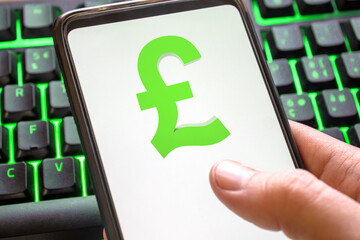 Smartphone with pound sterling lira symbol on screen phone with technology green colored keyboard background