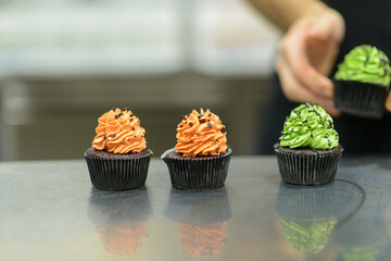 pastry chef baker preparing halloween green orange monster cupcakes handmade