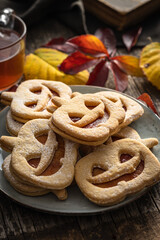 Linzer cookies in the shape of a Halloween pumpkin on wooden table.