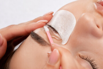 Make-up artist makes the procedure of lamination and dyeing of eyelashes to a beautiful woman in a...
